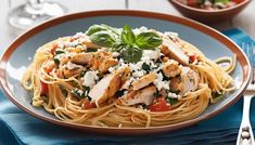 a plate of pasta with chicken, tomatoes and parmesan cheese on the side