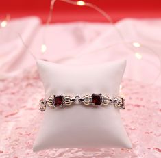 This bold bracelet features stations of square ruby red beads. The bracelet is made of durable stainless steel and has a spring ring clasp. The bracelet is 8 inches long and is a perfect fit for most wrists. Elegant Square Adjustable Bracelets, Elegant Red Chain Bracelet For Gift, Elegant Garnet Bracelets As Gift, Elegant Garnet Bracelet As Gift, Elegant Garnet Bracelet For Gift, Red Formal Bracelet Jewelry, Elegant Silver Square Bracelet, Modern Red Ruby Jewelry, Rectangular Red Garnet Jewelry