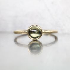 Olive Dot is a delicate yellow gold cabochon ring. A pale green sapphire from Montana is bezel set atop a round profile shank. Such a sweet design that can be stacked with other rings or worn by itself. I love the subtle color contrast between the olive green gemstone (5mm) and the warmth of the 14k yellow gold setting. If you love the idea of an understated American gemstone ring look no further! By the way, sapphire is September's birthstone. Shank measures 1.26mm. Gemstone weighs 0.81ct. Size Montana Sapphire, Yellow Gold Setting, Cabochon Ring, Green Sapphire, September Birthstone, Green Gemstones, Delicate Rings, Yellow Gold Ring, Pale Green