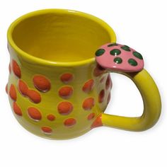 a yellow and pink coffee cup with a ladybug on it's side