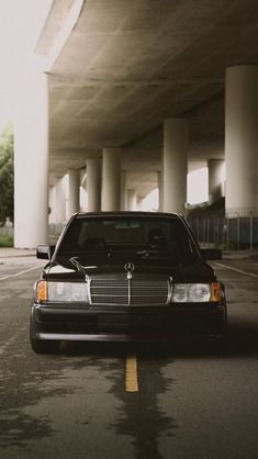 a black car is parked under an overpass