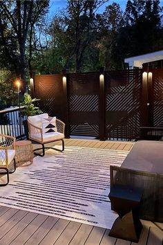 an outdoor deck with chairs and lights on the side, along with a rug that has been placed in front of it