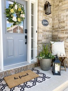 a blue front door with a welcome mat and two lanterns on the steps next to it