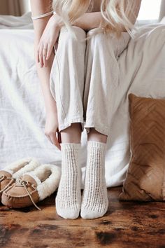 a woman sitting on top of a bed wearing white socks