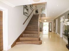 a staircase leading up to a living room with pictures on the wall and doors open