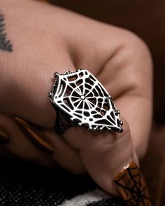 Step into the intricate world of mystery and elegance with this stainless steel ring, artfully shaped like a delicate spiderweb. Inspired by the masterful craftsmanship of arachnids, this ring captures the ethereal beauty and enigmatic charm of nature's most skilled weavers. The ring's design features a web of finely detailed stainless steel strands, intricately woven to mimic the complexity of a spider's silk creation. Each strand delicately crisscrosses to form a mesmerizing pattern, symbolizi Full Finger Ring, Halloween Chic, Pumpkin Cutouts, Spider Silk, Gothic Princess, Full Finger Rings, Sassy Dress, Bling Accessories, Vintage Inspired Fashion