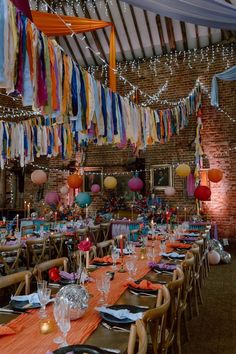 a long table is set up for a party with colorful streamers hanging from the ceiling