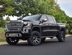 a black truck is parked on the side of the road in front of some trees