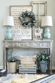 a table with two lamps and some plants on it in front of a framed sign