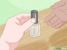 two hands holding an empty bottle on top of a wooden table next to another hand