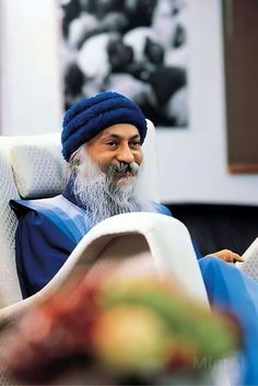 an old man sitting in a chair with a blue turban