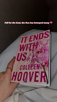 a person is holding a book in their hand on a bed with the title it ends with us, collien hoover