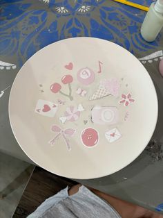 a white plate sitting on top of a table covered in stickers and paper flowers