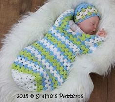 a baby sleeping in a crocheted blue and green blanket