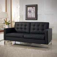 a living room with a black leather couch and white rug on top of the floor