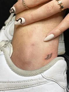 a woman's hand with white and black nail polishes on her left wrist