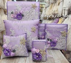 four purple pillows and two matching pillow cases with flowers on them are sitting on a wooden table