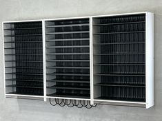 a wall mounted book shelf filled with lots of black and white books next to a gray wall