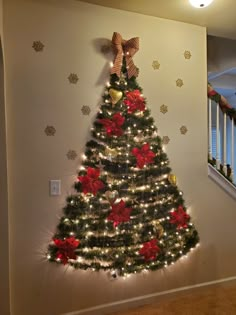 a decorated christmas tree with red and gold ornaments on the top, against a white wall