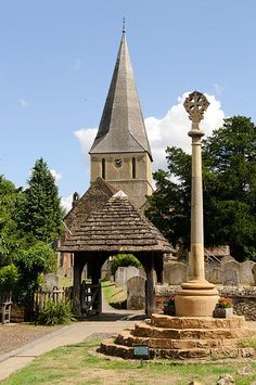 an old building with a tower and a clock on the top is surrounded by greenery