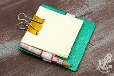 a notepad and pen sitting on top of a wooden table next to a pair of scissors