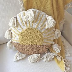 a white chair with a yellow blanket on top of it and a decorative pillow behind it