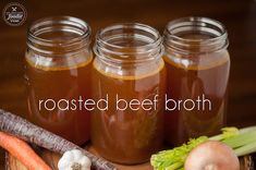 three jars filled with food sitting on top of a wooden table next to carrots and celery