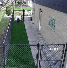 a fenced in area next to a building with grass growing on the ground and lawn