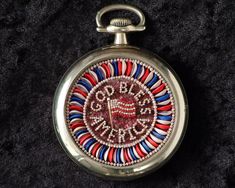 a red, white and blue beaded pocket watch on a black velvet cloth background