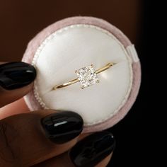 a close up of a person holding a ring with a diamond on the middle of it