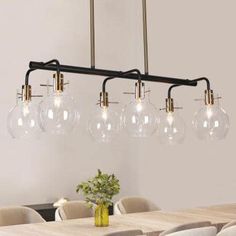 a chandelier hanging over a dining room table with six clear glass globes