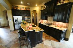 a large kitchen with black cabinets and granite counter tops