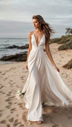 a woman in a white dress is walking on the beach