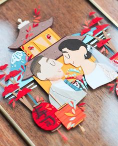 an image of a couple kissing in the middle of paper cut outs on a wooden table