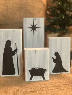 three wooden blocks decorated with black and white nativity silhouettes