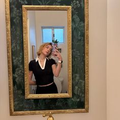 a woman taking a selfie in front of a mirror with a plant on it