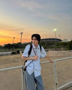 a man standing on the side of a road next to a fence with a camera in his hand