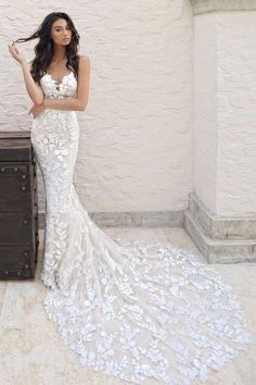 a woman in a white wedding dress standing next to a dresser and chest with flowers on it