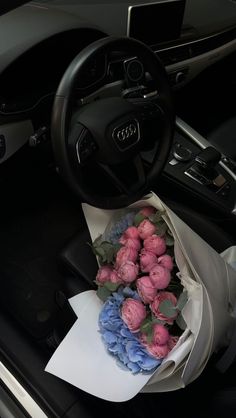 a bouquet of pink and blue flowers sitting in the center of a car's dashboard