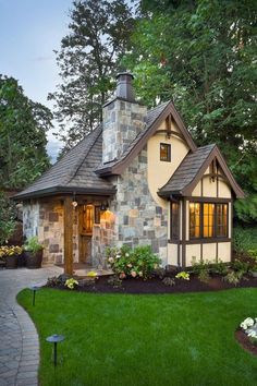 a small stone house with a wood door and windows in the front yard, surrounded by greenery