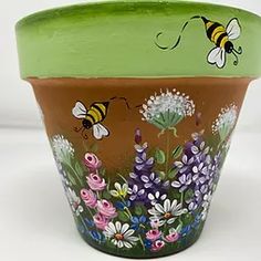 a flower pot painted with bees and flowers on it's sides, sitting in front of a white background