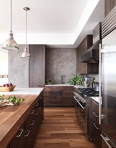 a modern kitchen with wood floors and stainless steel appliances, including an island countertop