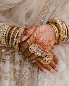 a close up of a person's hands with bracelets and rings on them