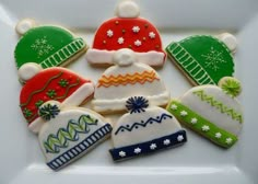 decorated cookies in the shape of hats and mittens are on a white platter