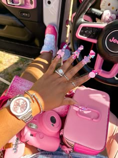 a woman's hand on the steering wheel of a car with her pink purse