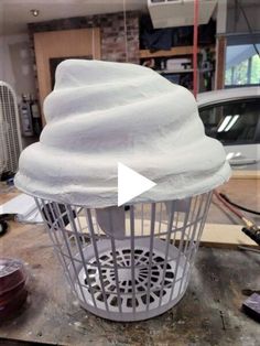 a white birdcage sitting on top of a wooden table next to a car