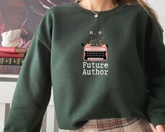 You'll love this future author crewneck sweatshirt! The soft, comfy material is made from a blend of cotton and polyester. There are no itchy side seems and it has a trendy, loose fit. This bookish sweatshirt is a great gift for the ambitious writers in your life. Please use the sizing guide for additional guidance on sizing! This Sweatshirt is a Unisex-style, so it has a smaller fit than men's sizing, but a little larger fit than women's sizing. Please size up 1-2 sizes for the Oversized Look. Bookish Sweatshirt With Letter Print And Crew Neck, Bookish Cotton Sweatshirt For Winter, Relaxed Fit Bookish Sweatshirt For Fall, Winter Cotton Sweatshirt, Winter Bookish Cotton Sweatshirt, Relaxed Fit Crew Neck Bookish Sweatshirt, Bookish Crew Neck Sweatshirt For Winter, Light Academia Clothes, Author Gifts