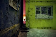 an alley way with snow on the ground and a green door leading to a window