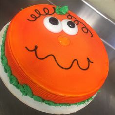 an orange cake decorated with green leaves and eyes