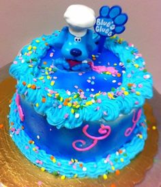 a blue cake with sprinkles and a dog on top that says blue's clues